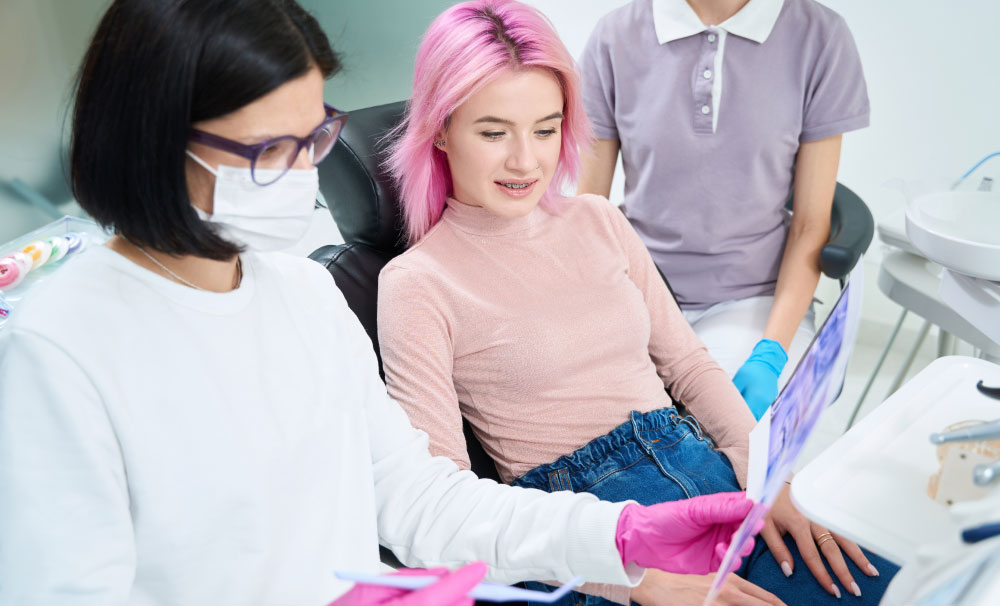 A teenage girl and an orthodontist viewing exam results in the orthodontist's office.